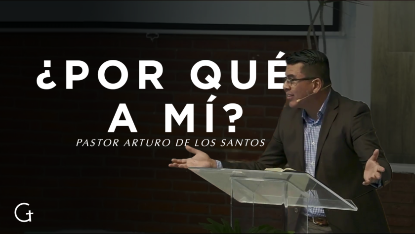 El pastor Arturo de los Santos con los brazos extendidos parado frente a un atril transparente. Detrás de él está el texto "¿por qué a mí?"